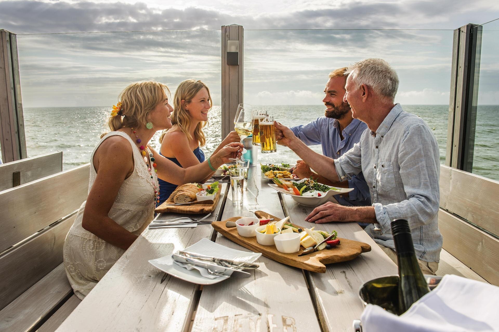 Freunde stoßen auf der Dachterrasse eines Pfahlbaurestaurants miteinander an