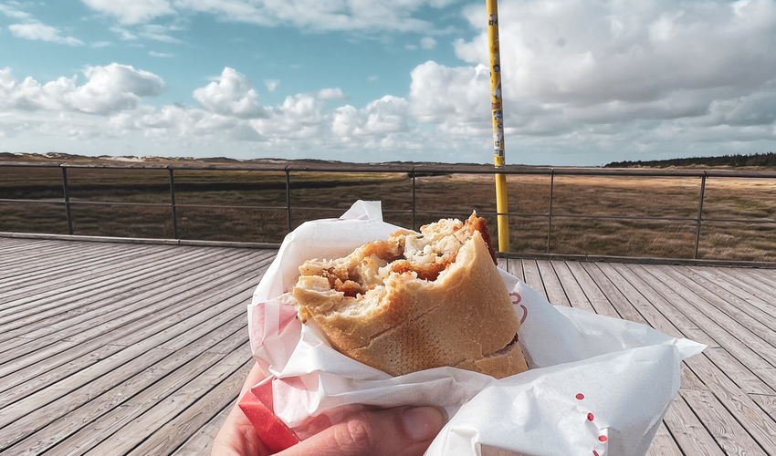 Hand hält Fischbrötchen auf dem Seebrückenvorplatz