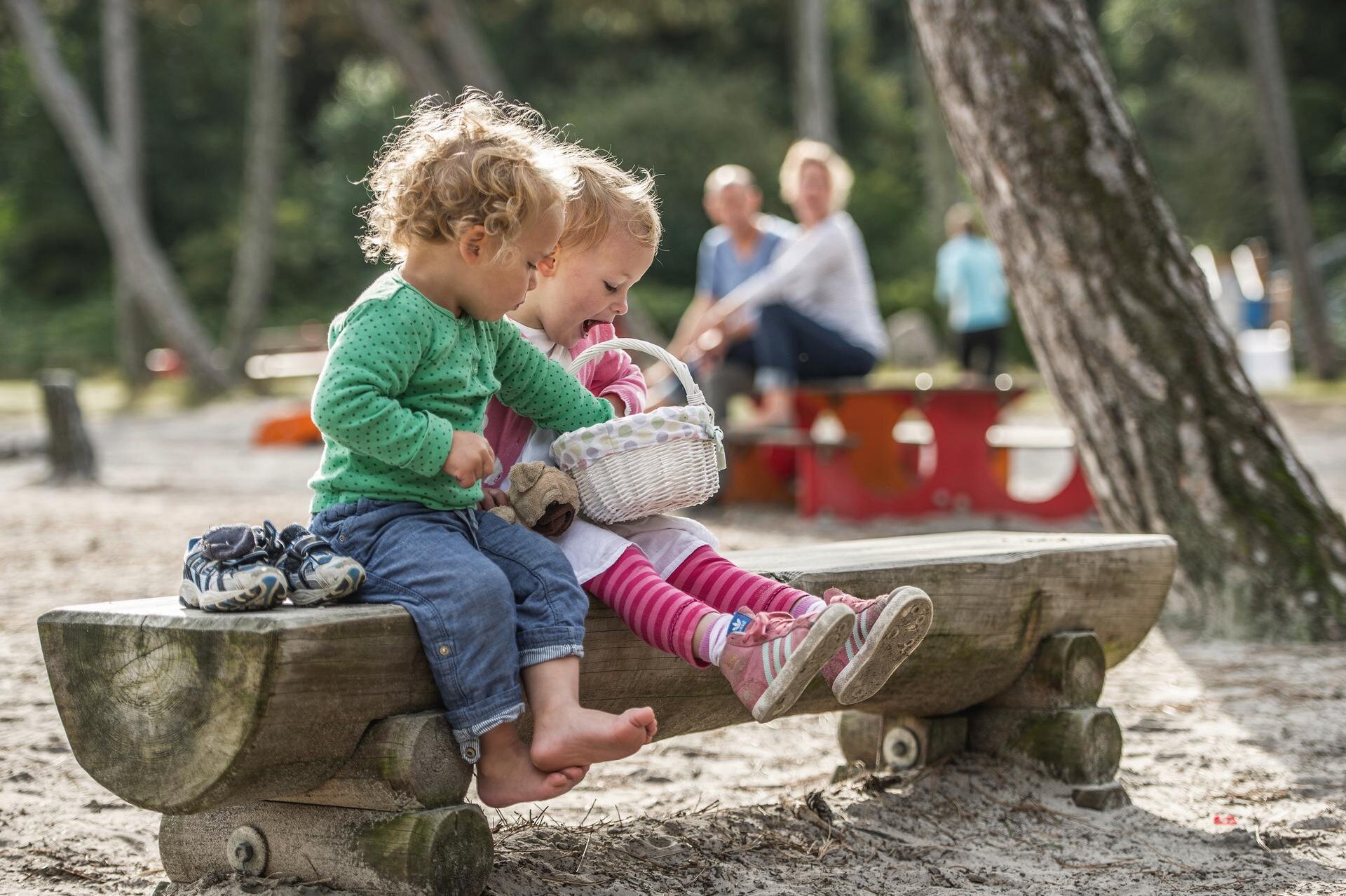 Kinder mit Osterkörbchen auf einer Bank auf dem Spielplatz