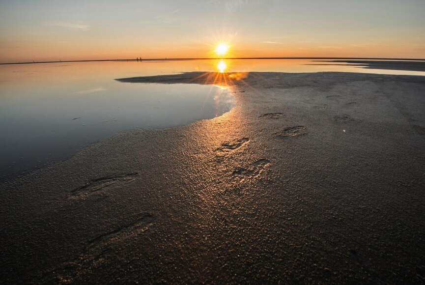 Fußspuren im Watt beim Sonnenuntergang