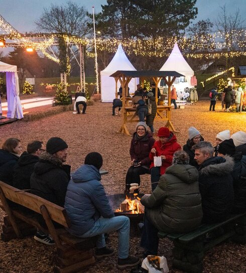 Personen auf Sitzbänken auf dem Weihnachtsmarkt