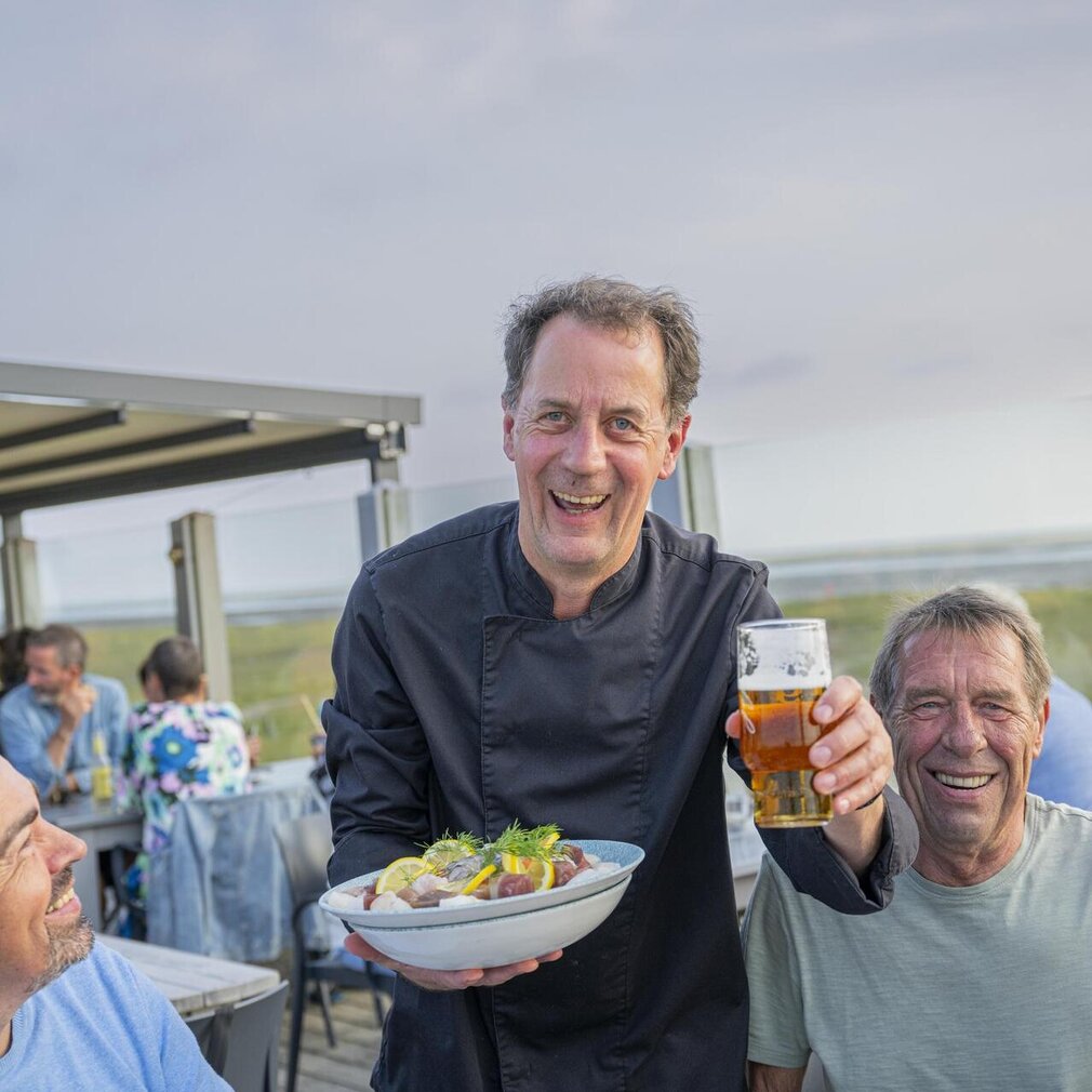Mann mit Gericht und Bier in der Hand