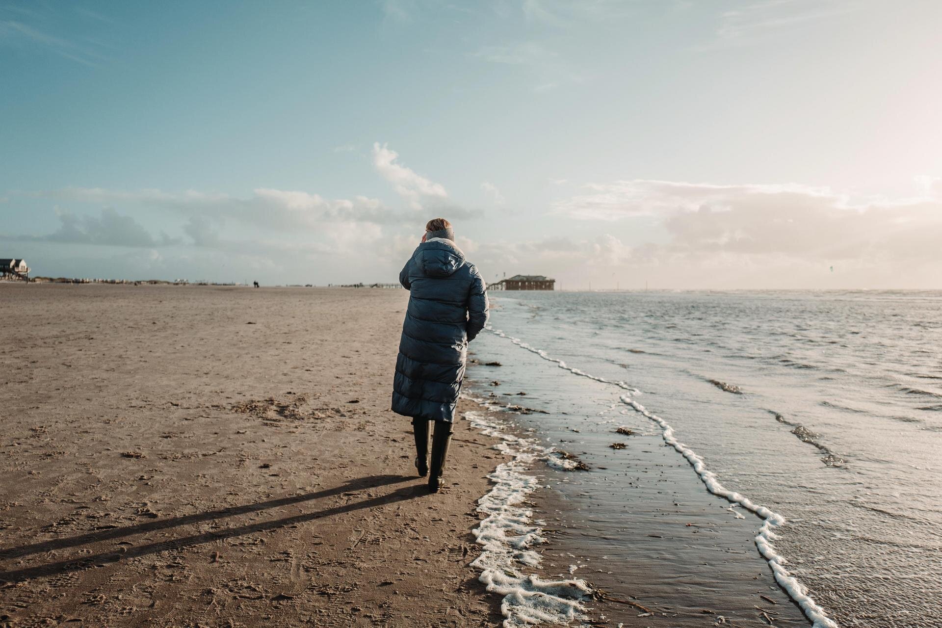 Frau spaziert an der Wasserkante im Herbst
