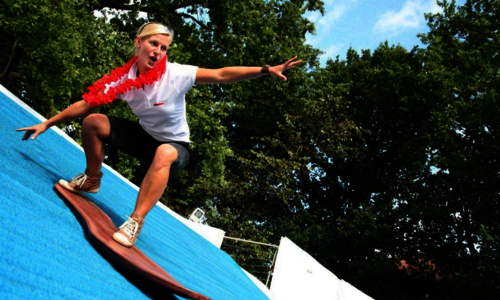 Ein Mädchen surft auf einem Surfsimulator.