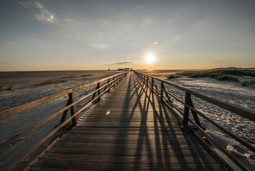 Seebrücke in Richtung Strand beim Sonnenuntergang