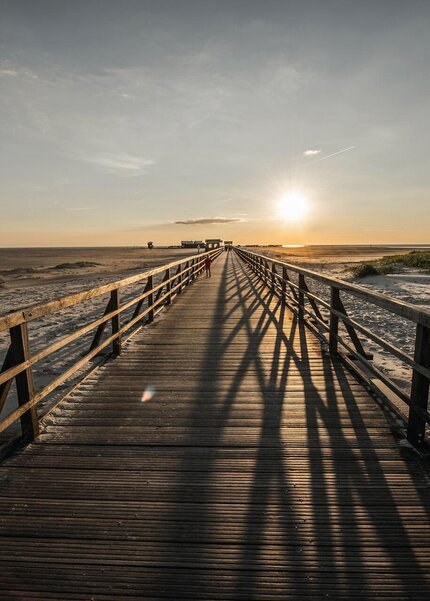 Seebrücke in Richtung Strand beim Sonnenuntergang