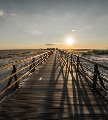 Seebrücke beim Sonnenuntergang in Richtung Strand