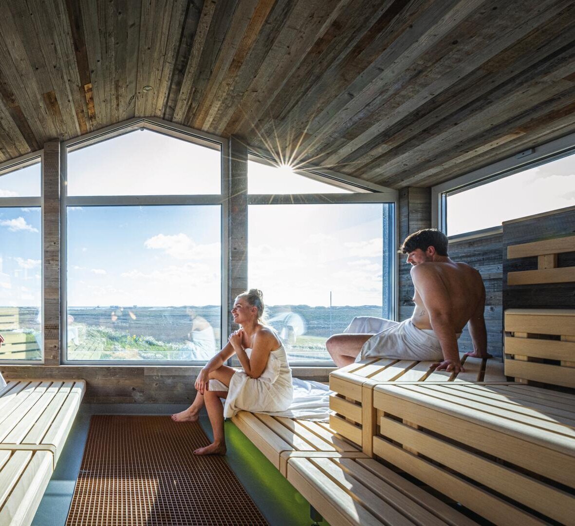 Personen entspannen in der Pfahlbausauna mit Panoramafenster