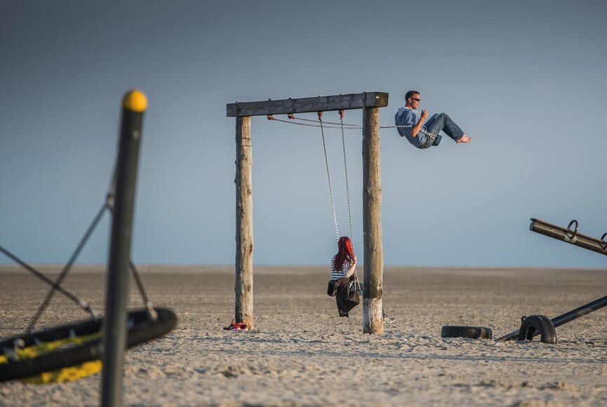 Stranspielplatz mit Schaukelnden Personen