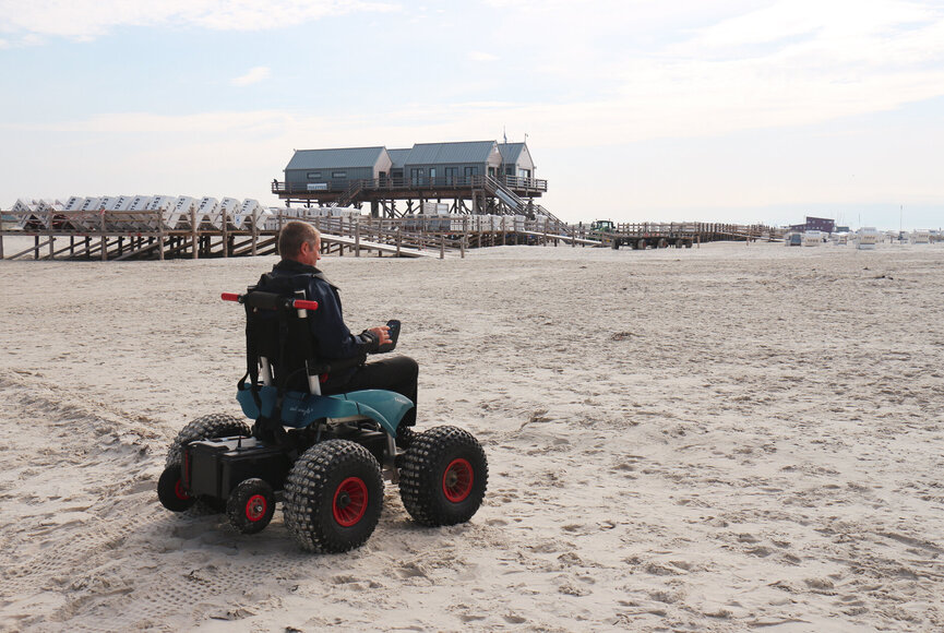 sympathischer Mann nutzt den elektrischen Strandrollstuhl