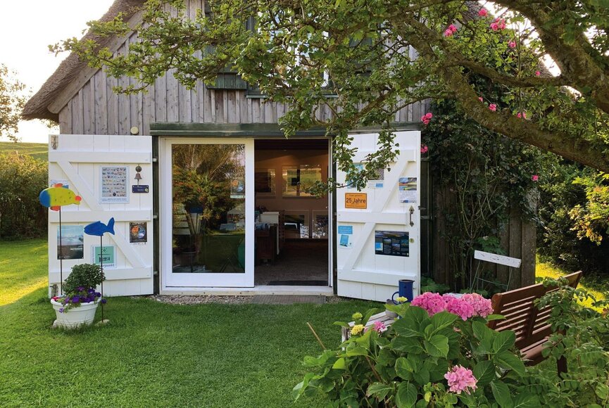 Außenansicht der Galerie "Meerkunst" in einem kleinen Holzhaus mit Reetdach