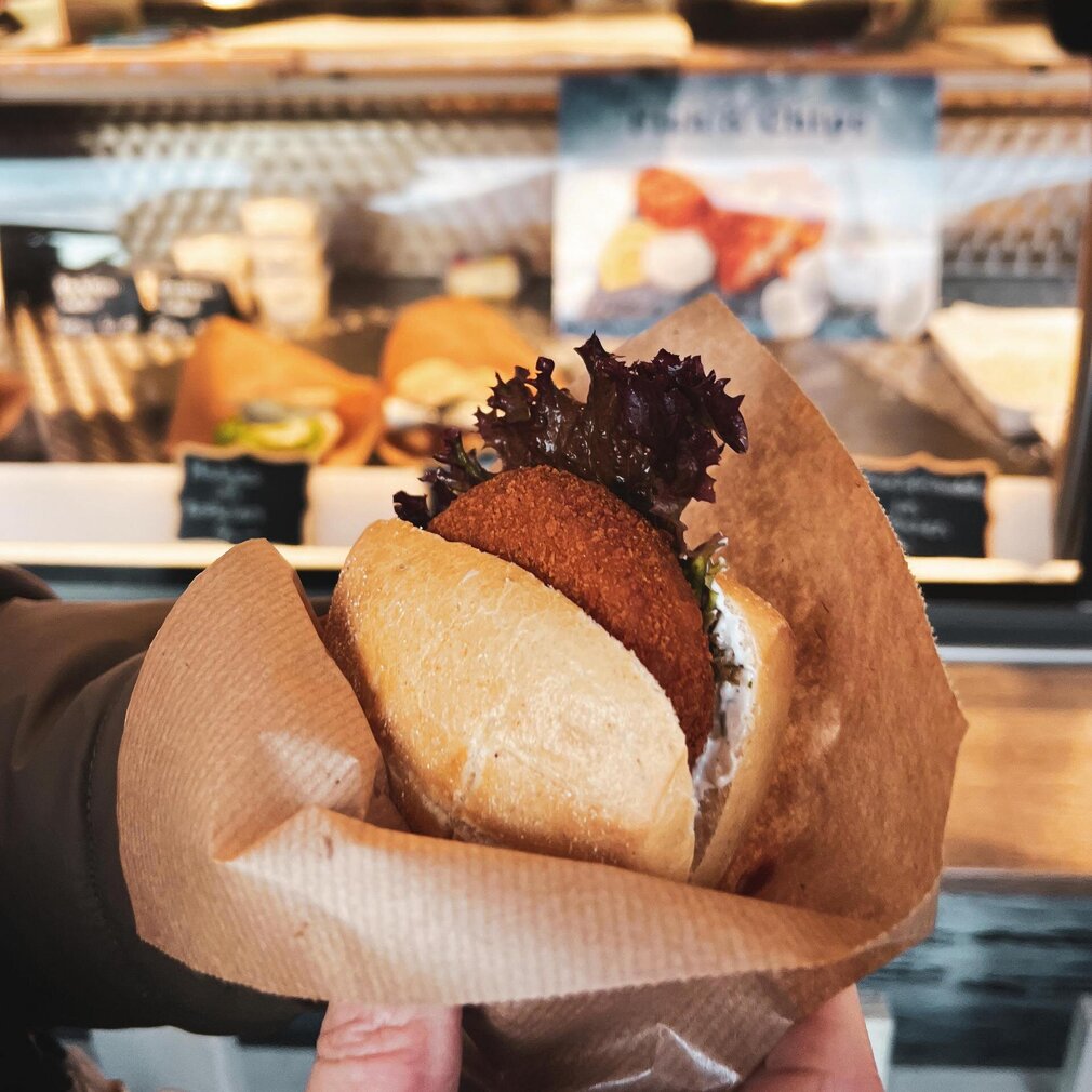 Hand hält Fischbrötchen in Papier