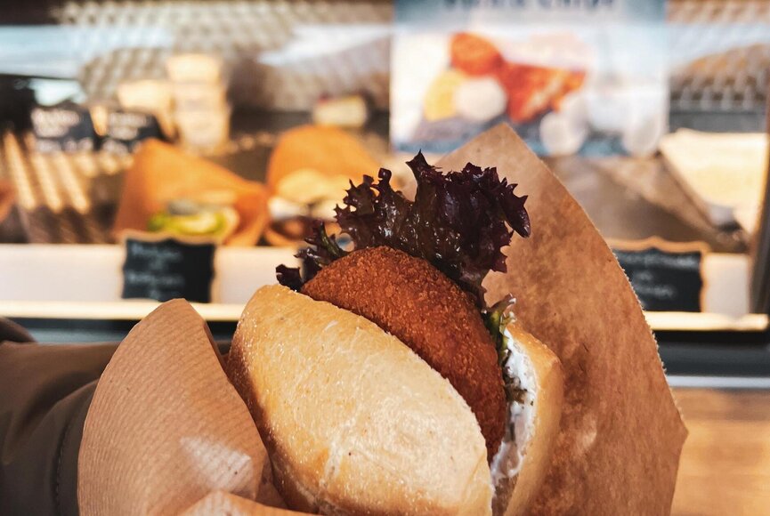 Hand hält ein Fischbrötchen mit Fischfrikadelle
