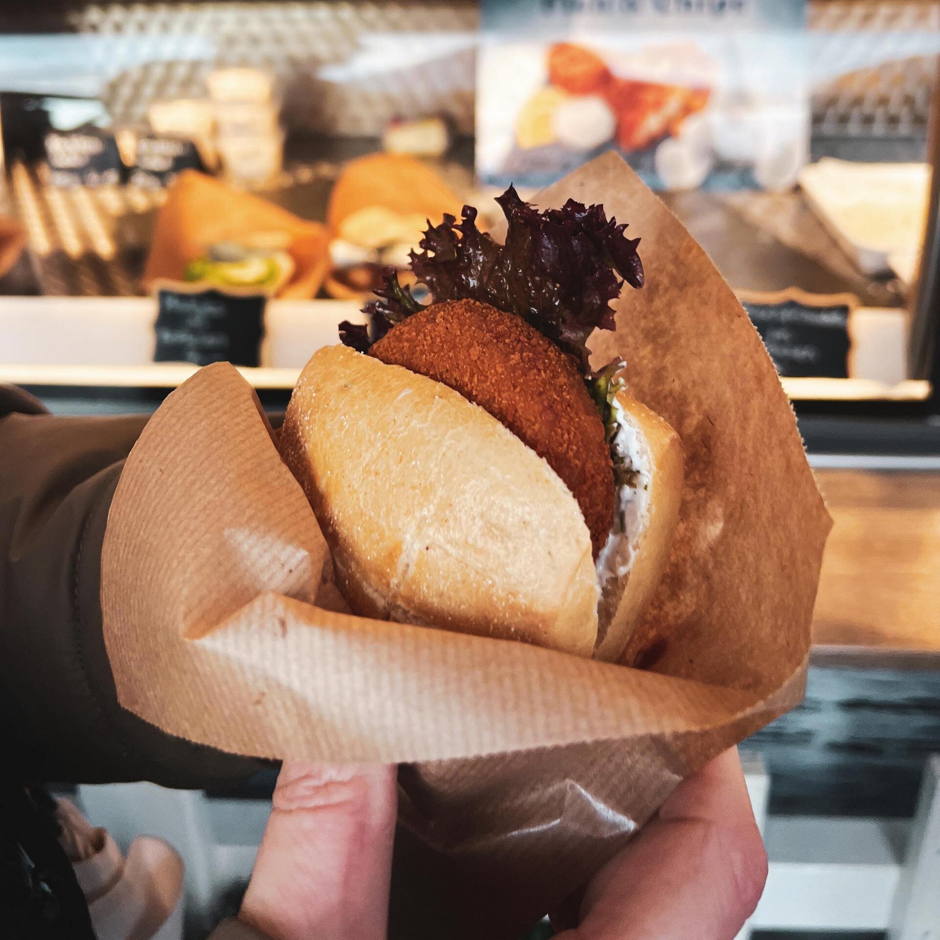 Hand hält Fischbrötchen in Papier 