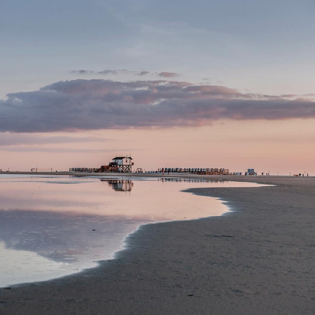 Pfahlbau und Priel bei abendlichem Licht am Strand